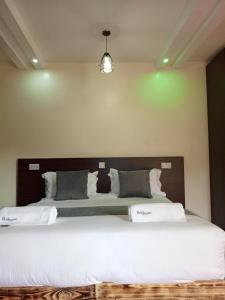 een slaapkamer met een groot bed met witte lakens bij The Grand Alton Resort Kisumu in Kisumu