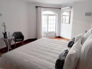 a bedroom with a large bed with a chair and a window at Luso Village Boutique Hotel in Luso