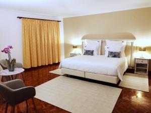 a bedroom with a large white bed and a chair at Luso Village Boutique Hotel in Luso