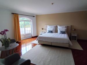 a bedroom with a white bed and a large window at Luso Village Boutique Hotel in Luso