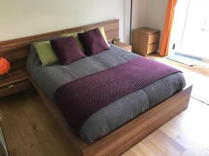 a bed with purple and green pillows in a room at Large cosy flat in Southbourne near beaches in Bournemouth