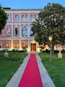 een roze gebouw met een rode loper ervoor bij San Clemente Palace Kempinski Venice in Venetië