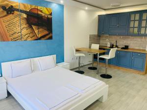 a bedroom with a white bed and a kitchen at Apartman Blue in Sombor