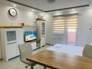 a dining room with a table and a clock on the wall at Apartman Blue in Sombor