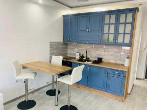 a kitchen with blue cabinets and a wooden table at Apartman Blue in Sombor