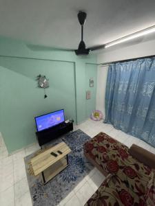 Blissful Breeze 4 ROOMS & NETFLIX by EZYROOM MELAKA في آير كيروه: غرفة معيشة مع تلفزيون وأريكة وطاولة