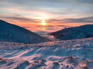 una montaña cubierta de nieve con la puesta de sol en el fondo en Plai, en Dragobrat