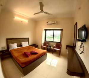 a bedroom with a bed and a television in it at Hotel Laxmibai Palace in Shirdi