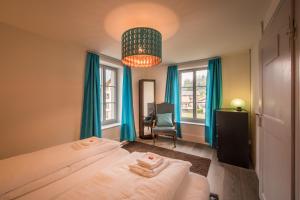 a bedroom with two beds with blue curtains and a chandelier at Dependance Penthouse in Interlaken