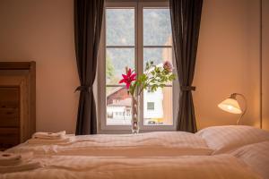 a bedroom with a bed and a window with a vase of flowers at Dependance Penthouse in Interlaken