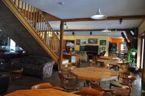 a restaurant with wooden tables and chairs and a staircase at Auberge jeunesse de Tadoussac in Tadoussac