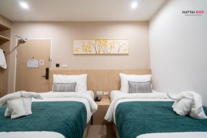 two beds in a room with green and white at Chinatown Living Hatyai in Hat Yai