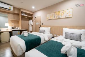 a hotel room with two beds and a desk at Chinatown Living Hatyai in Hat Yai