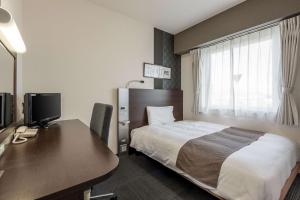 een hotelkamer met een bed en een bureau met een computer bij Comfort Hotel Koriyama in Koriyama