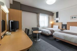 een hotelkamer met 2 bedden en een bureau met een televisie bij Comfort Hotel Koriyama in Koriyama