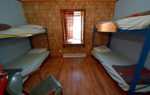 a room with three bunk beds and a window at Auberge jeunesse de Tadoussac in Tadoussac