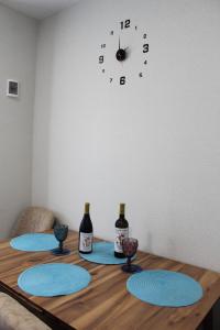 a table with three bottles of wine and a clock on a wall at Kitesa's cozy apartment in Mtskheta