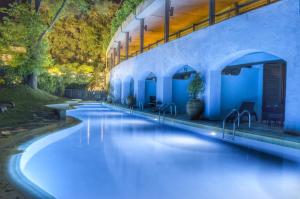 - une piscine avec des lumières bleues sur le côté d'un bâtiment dans l'établissement Corfu Holiday Palace, à Corfou