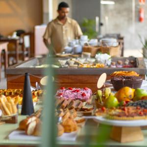 um homem de pé numa cozinha com um buffet de comida em Apenunga Eco Hotel em Jericoacoara