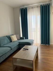 uma sala de estar com um sofá azul e uma mesa de centro em Jur Apartment em Durrës