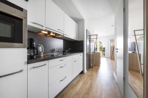 Il comprend une cuisine avec des placards blancs et du parquet. dans l'établissement Livingroom Bad Homburg Boardinghouse, à Bad Homburg vor der Höhe