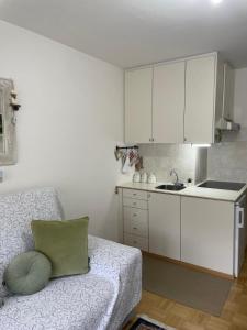 a kitchen with white cabinets and a couch in a room at Condominio - Guglielmo Tell in Sestriere