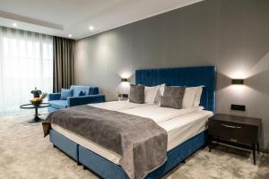 um quarto de hotel com uma cama grande e uma cadeira azul em Empire Balneo & Spa Hotel em Hisarya