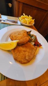 une plaque blanche avec du poisson, des frites et un citron dans l'établissement Landgasthof zum Glenner, à Ilanz