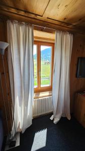 Cette chambre avec vue dispose d'une fenêtre avec des rideaux blancs. dans l'établissement Landgasthof zum Glenner, à Ilanz