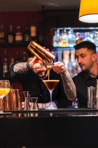 a bartender making a drink at a bar at Unique Hotel Post in Zermatt