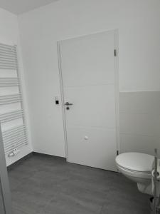 een witte badkamer met een toilet en een deur bij D&M Apartament Buchholz Sprötze in Buchholz in der Nordheide