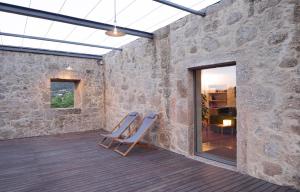 un patio de piedra amurallado con 2 sillas en una terraza en Quinta do Outeiro 1598, en Ponte da Barca