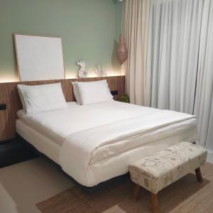 um quarto com uma grande cama branca e um banco em Contessa Suites em Lefkada Town