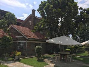 a table with an umbrella in front of a house at Taphe Resort Naivasha in Naivasha