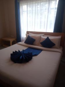 a bed with blue and white pillows and a window at Taphe Resort Naivasha in Naivasha