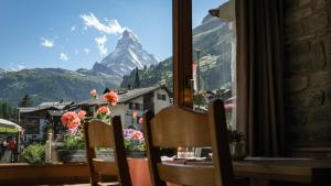 a table with chairs and a view of a mountain at Hotel Parnass in Zermatt