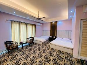 a bedroom with two beds and a table and chairs at Hotel Grand Akther in Sylhet