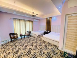 a bedroom with two beds and chairs and a ceiling at Hotel Grand Akther in Sylhet