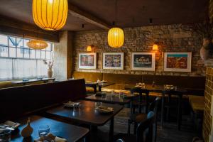 uma sala de jantar com mesas, cadeiras e luzes em Highway em Burford