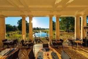 un patio con tavoli, sedie e vista sul lago di Garrigae Manoir de Beauvoir Poitiers Sud - Hotel & Spa a Mignaloux-Beauvoir