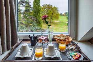 un tavolo con un vassoio di prodotti per la colazione e una finestra di Garrigae Manoir de Beauvoir Poitiers Sud - Hotel & Spa a Mignaloux-Beauvoir