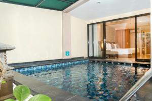 una piscina en una habitación de hotel con un dormitorio en Cross Vibe Paasha Atelier Bali Kuta en Kuta