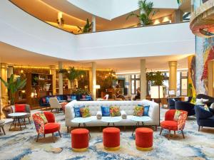 a lobby with a white couch and red chairs at Sofitel Brussels Europe in Brussels