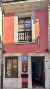 un edificio rojo con dos ventanas y una puerta en La Posada del Rey, en Llanes