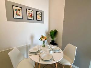 a white dining room table with white chairs and a vase of flowers at Apartment am Lutherplatz in Potsdam