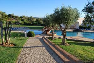 una pasarela junto a una piscina con árboles en Casa Campo & Mar, en Mexilhoeira Grande