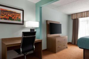 una camera d'albergo con letto e scrivania con TV di Wingate by Wyndham Louisville East a Louisville