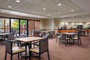 una sala da pranzo con tavoli, sedie e finestre di Wingate by Wyndham Louisville East a Louisville