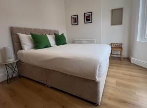 una camera da letto con un grande letto con cuscini verdi di Liverpool Cherry House - 4 Bedrooms a Liverpool