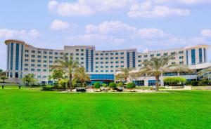 a large building with palm trees in front of it at Crowne Plaza Muscat OCEC, an IHG Hotel in Muscat